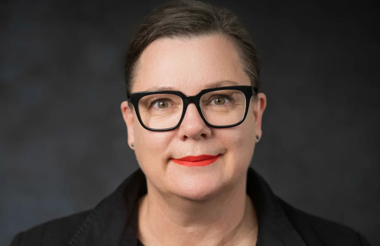 Arts South Australia CEO Christine Schloithe wearing black-rimmed glasses and red lipstick posing for an official professional headshot portrait.